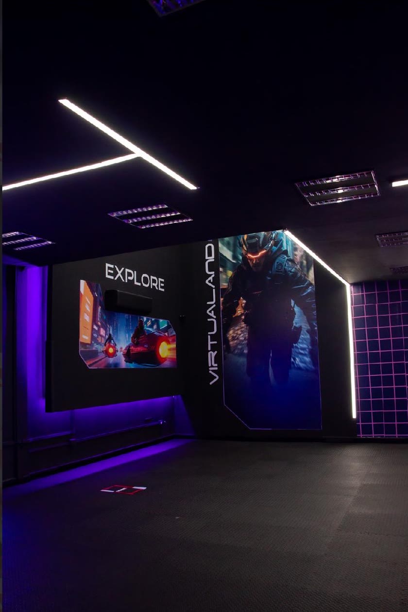 La arena de Virtualand: piso amplio, luces de neón moradas y muros con arte futurista