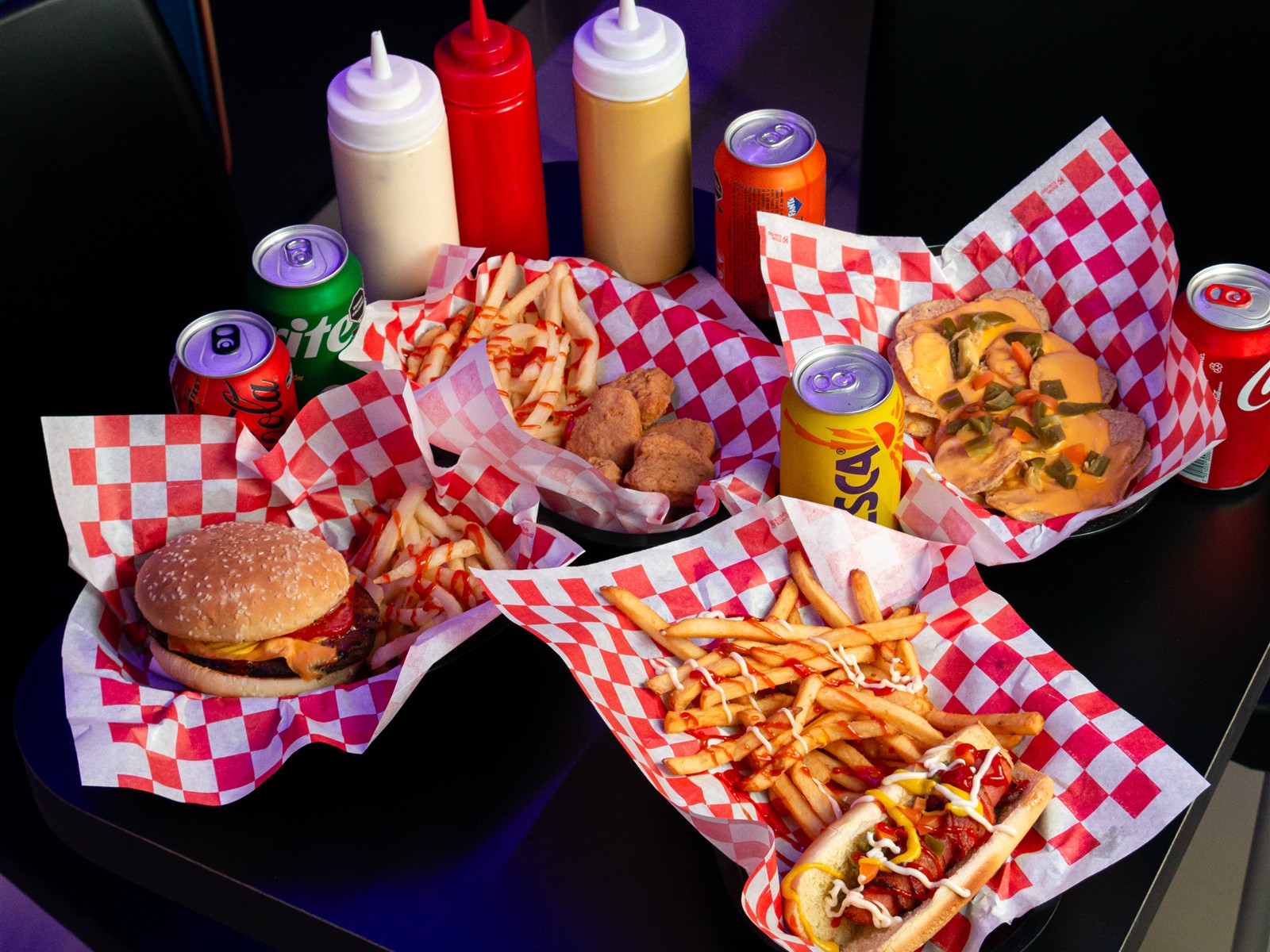 Mesa con hamburguesa, nuggets, nachos con queso, papas, hot dog y refrescos de Virtualand